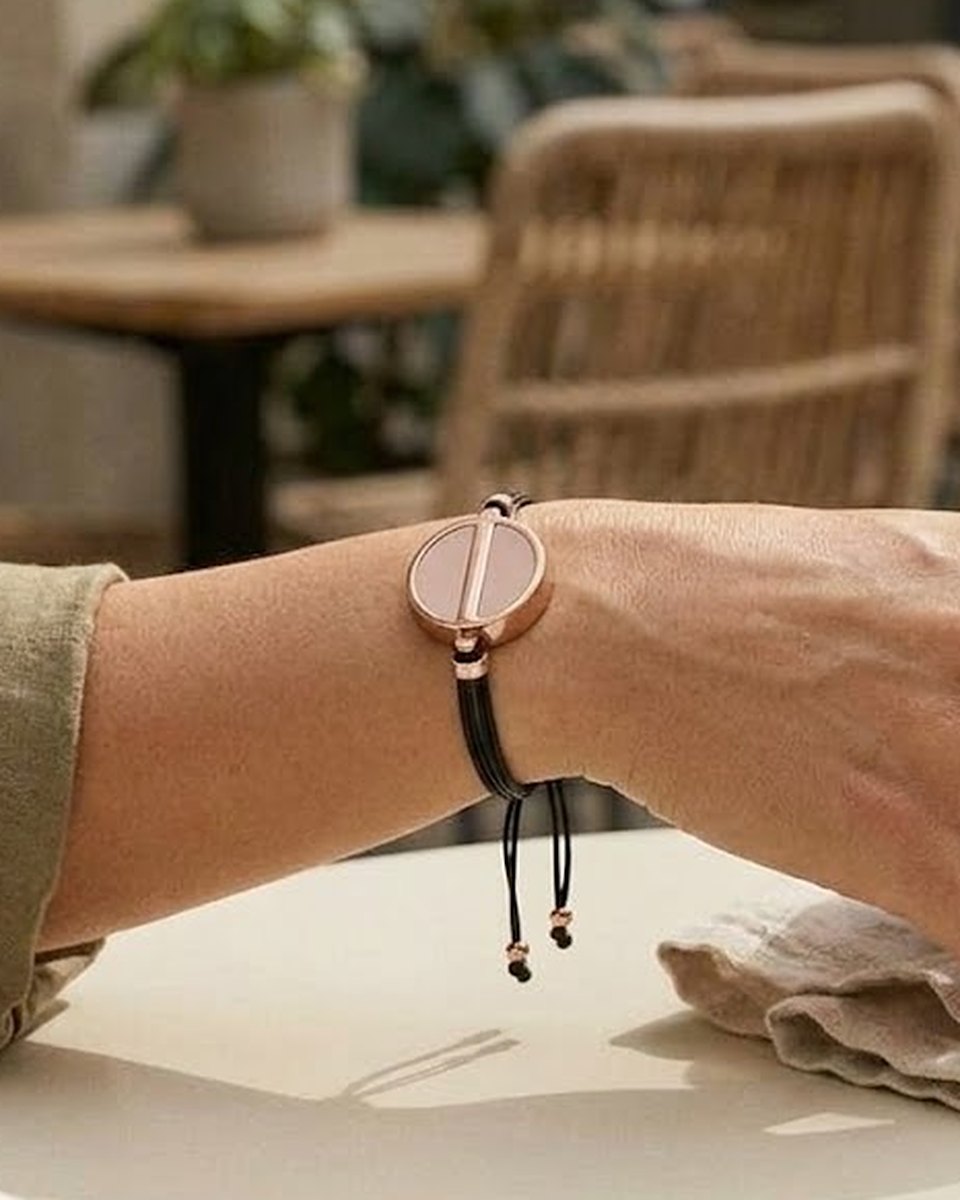 The Cord worn on the wrist: a silk cord with a sliding knot and the Charm at its center